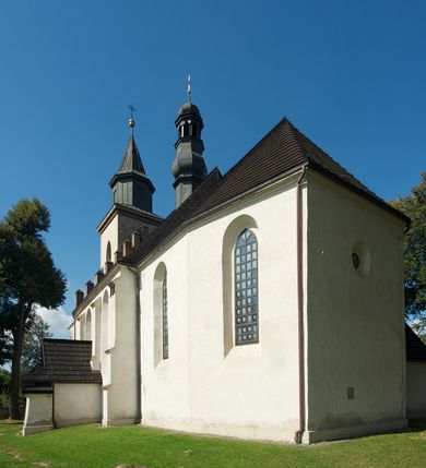 Zdjęcie nr 3: Kościół murowany z kamienia, z użyciem cegły, tynkowany; orientowany, jednonawowy. Prezbiterium węższe od nawy, zwężające się, na rzucie zbliżonym do trapezu. Przy północnej ścianie zakrystia w rzucie zbliżonym do kwadratu, z ukośną ścianą południową. Nawa na planie prostokąta, z przylegającymi od południa kruchtą i wieżą od zachodu na rzucie prostokąta. Nawa i zakrystia opięte szkarpami. 
Wnętrze nakryte stropami drewnianymi. Wątki ceglane i murowane ścian odsłonięte. Zamiast posadzki wylewka betonowa (posadzki kamienne zdemontowane). Otwór tęczowy półkolisty. Otwory okienne nawy i prezbiterium w liczbie czterech na południowej ścianie i jednego na północnej w części prezbiterium; w formie wydłużonego stojącego prostokąta zamkniętego półkoliście ze ściętymi glifami, bez obramień. Na ścianie zamykającej prezbiterium niewielki okulus. Na ścianie zachodniej niewielkie otwory okienne w formie stojącego prostokąta, dwa zamknięte ostrołukowo (przesłonięte), jeden zamknięty łukiem odcinkowym oraz dwa okulusy (zamurowane). Otwory okienne wieży ostrołukowe, z profilowanymi obramieniami kamiennymi. W zakrystii małe kwadratowe okienko przesłonięte kratownicą. Otwory drzwiowe: w wejściu do przyziemia wieży od zachodu, otwór w formie stojącego prostokąta zamkniętego łukiem ostrym, w kamiennym obramieniu zwieńczony kamienną tablicą (z datą budowy wieży „1868”), z drewnianymi drzwiami płycinowymi, dwuskrzydłowymi; w przejściu z przyziemia wieży do nawy otwór w formie stojącego prostokąta zamkniętego półkoliście (pierwotnie zamkniętego łukiem odcinkowym), przesłonięty metalową kratą; w wejściu do kruchty południowej otwór w formie stojącego prostokąta zamknięty łukiem odcinkowym, z drzwiami płycinowymi, dwuskrzydłowymi; w przejściu z kruchty do nawy otwór w formie stojącego prostokąta zamknięty półkoliście z drewnianymi drzwiami z okuciami, zamkiem i antabą; w wejściu do zakrystii od zewnętrz otwór prostokątny, z drzwiami jednoskrzydłowymi, płycinowymi; w przejściu z zakrystii do nawy otwór w formie stojącego prostokąta, w kamiennym obramieniu, z drzwiami z okuciami i zamkiem. Elewacje tynkowane, zamknięte profilowanymi gzymsami podokapowymi. Nawa, zakrystia i kruchta opięte szkarpami (przy nawie uskokowymi z daszkami okapowymi). Fasada zamknięta ceglanym szczytem, dekorowanym schodkowym krenelażem, z dwoma niewielkimi, smukłymi otworami okiennymi zamkniętymi ostrołukowo. 
Wieża trójkondygnacyjna, bez podziałów architektonicznych, druga kondygnacja zamknięta daszkiem okapowym. Zwieńczona dachem namiotowym z latarnią na planie ośmioboku, zamkniętą dachem wieżowym, pobitym blachą.
Pierwotne dachy siodłowe, o odrębnych kalenicach dla nawy i prezbiterium, kryte gontem; więźba drewniana, konstrukcji krokwiowej. Nad nawą wieżyczka na sygnaturkę z hełmem baniastym z latarnią, kryta blachą. Kruchtę przykrywa dach dwuspadowy, kryty gontem. 
