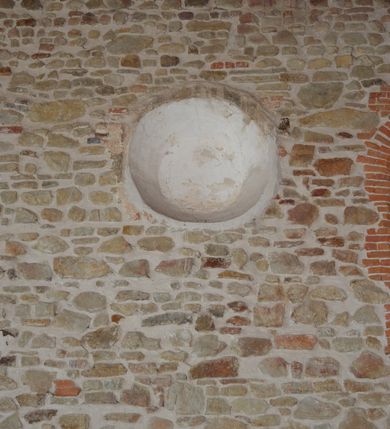 Zdjęcie nr 8: Kościół murowany z kamienia, z użyciem cegły, tynkowany; orientowany, jednonawowy. Prezbiterium węższe od nawy, zwężające się, na rzucie zbliżonym do trapezu. Przy północnej ścianie zakrystia w rzucie zbliżonym do kwadratu, z ukośną ścianą południową. Nawa na planie prostokąta, z przylegającymi od południa kruchtą i wieżą od zachodu na rzucie prostokąta. Nawa i zakrystia opięte szkarpami. 
Wnętrze nakryte stropami drewnianymi. Wątki ceglane i murowane ścian odsłonięte. Zamiast posadzki wylewka betonowa (posadzki kamienne zdemontowane). Otwór tęczowy półkolisty. Otwory okienne nawy i prezbiterium w liczbie czterech na południowej ścianie i jednego na północnej w części prezbiterium; w formie wydłużonego stojącego prostokąta zamkniętego półkoliście ze ściętymi glifami, bez obramień. Na ścianie zamykającej prezbiterium niewielki okulus. Na ścianie zachodniej niewielkie otwory okienne w formie stojącego prostokąta, dwa zamknięte ostrołukowo (przesłonięte), jeden zamknięty łukiem odcinkowym oraz dwa okulusy (zamurowane). Otwory okienne wieży ostrołukowe, z profilowanymi obramieniami kamiennymi. W zakrystii małe kwadratowe okienko przesłonięte kratownicą. Otwory drzwiowe: w wejściu do przyziemia wieży od zachodu, otwór w formie stojącego prostokąta zamkniętego łukiem ostrym, w kamiennym obramieniu zwieńczony kamienną tablicą (z datą budowy wieży „1868”), z drewnianymi drzwiami płycinowymi, dwuskrzydłowymi; w przejściu z przyziemia wieży do nawy otwór w formie stojącego prostokąta zamkniętego półkoliście (pierwotnie zamkniętego łukiem odcinkowym), przesłonięty metalową kratą; w wejściu do kruchty południowej otwór w formie stojącego prostokąta zamknięty łukiem odcinkowym, z drzwiami płycinowymi, dwuskrzydłowymi; w przejściu z kruchty do nawy otwór w formie stojącego prostokąta zamknięty półkoliście z drewnianymi drzwiami z okuciami, zamkiem i antabą; w wejściu do zakrystii od zewnętrz otwór prostokątny, z drzwiami jednoskrzydłowymi, płycinowymi; w przejściu z zakrystii do nawy otwór w formie stojącego prostokąta, w kamiennym obramieniu, z drzwiami z okuciami i zamkiem. Elewacje tynkowane, zamknięte profilowanymi gzymsami podokapowymi. Nawa, zakrystia i kruchta opięte szkarpami (przy nawie uskokowymi z daszkami okapowymi). Fasada zamknięta ceglanym szczytem, dekorowanym schodkowym krenelażem, z dwoma niewielkimi, smukłymi otworami okiennymi zamkniętymi ostrołukowo. 
Wieża trójkondygnacyjna, bez podziałów architektonicznych, druga kondygnacja zamknięta daszkiem okapowym. Zwieńczona dachem namiotowym z latarnią na planie ośmioboku, zamkniętą dachem wieżowym, pobitym blachą.
Pierwotne dachy siodłowe, o odrębnych kalenicach dla nawy i prezbiterium, kryte gontem; więźba drewniana, konstrukcji krokwiowej. Nad nawą wieżyczka na sygnaturkę z hełmem baniastym z latarnią, kryta blachą. Kruchtę przykrywa dach dwuspadowy, kryty gontem. 
