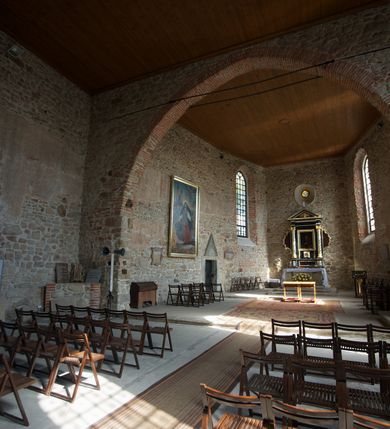 Zdjęcie nr 12: Kościół murowany z kamienia, z użyciem cegły, tynkowany; orientowany, jednonawowy. Prezbiterium węższe od nawy, zwężające się, na rzucie zbliżonym do trapezu. Przy północnej ścianie zakrystia w rzucie zbliżonym do kwadratu, z ukośną ścianą południową. Nawa na planie prostokąta, z przylegającymi od południa kruchtą i wieżą od zachodu na rzucie prostokąta. Nawa i zakrystia opięte szkarpami. 
Wnętrze nakryte stropami drewnianymi. Wątki ceglane i murowane ścian odsłonięte. Zamiast posadzki wylewka betonowa (posadzki kamienne zdemontowane). Otwór tęczowy półkolisty. Otwory okienne nawy i prezbiterium w liczbie czterech na południowej ścianie i jednego na północnej w części prezbiterium; w formie wydłużonego stojącego prostokąta zamkniętego półkoliście ze ściętymi glifami, bez obramień. Na ścianie zamykającej prezbiterium niewielki okulus. Na ścianie zachodniej niewielkie otwory okienne w formie stojącego prostokąta, dwa zamknięte ostrołukowo (przesłonięte), jeden zamknięty łukiem odcinkowym oraz dwa okulusy (zamurowane). Otwory okienne wieży ostrołukowe, z profilowanymi obramieniami kamiennymi. W zakrystii małe kwadratowe okienko przesłonięte kratownicą. Otwory drzwiowe: w wejściu do przyziemia wieży od zachodu, otwór w formie stojącego prostokąta zamkniętego łukiem ostrym, w kamiennym obramieniu zwieńczony kamienną tablicą (z datą budowy wieży „1868”), z drewnianymi drzwiami płycinowymi, dwuskrzydłowymi; w przejściu z przyziemia wieży do nawy otwór w formie stojącego prostokąta zamkniętego półkoliście (pierwotnie zamkniętego łukiem odcinkowym), przesłonięty metalową kratą; w wejściu do kruchty południowej otwór w formie stojącego prostokąta zamknięty łukiem odcinkowym, z drzwiami płycinowymi, dwuskrzydłowymi; w przejściu z kruchty do nawy otwór w formie stojącego prostokąta zamknięty półkoliście z drewnianymi drzwiami z okuciami, zamkiem i antabą; w wejściu do zakrystii od zewnętrz otwór prostokątny, z drzwiami jednoskrzydłowymi, płycinowymi; w przejściu z zakrystii do nawy otwór w formie stojącego prostokąta, w kamiennym obramieniu, z drzwiami z okuciami i zamkiem. Elewacje tynkowane, zamknięte profilowanymi gzymsami podokapowymi. Nawa, zakrystia i kruchta opięte szkarpami (przy nawie uskokowymi z daszkami okapowymi). Fasada zamknięta ceglanym szczytem, dekorowanym schodkowym krenelażem, z dwoma niewielkimi, smukłymi otworami okiennymi zamkniętymi ostrołukowo. 
Wieża trójkondygnacyjna, bez podziałów architektonicznych, druga kondygnacja zamknięta daszkiem okapowym. Zwieńczona dachem namiotowym z latarnią na planie ośmioboku, zamkniętą dachem wieżowym, pobitym blachą.
Pierwotne dachy siodłowe, o odrębnych kalenicach dla nawy i prezbiterium, kryte gontem; więźba drewniana, konstrukcji krokwiowej. Nad nawą wieżyczka na sygnaturkę z hełmem baniastym z latarnią, kryta blachą. Kruchtę przykrywa dach dwuspadowy, kryty gontem. 
