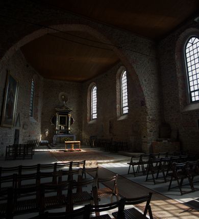 Zdjęcie nr 13: Kościół murowany z kamienia, z użyciem cegły, tynkowany; orientowany, jednonawowy. Prezbiterium węższe od nawy, zwężające się, na rzucie zbliżonym do trapezu. Przy północnej ścianie zakrystia w rzucie zbliżonym do kwadratu, z ukośną ścianą południową. Nawa na planie prostokąta, z przylegającymi od południa kruchtą i wieżą od zachodu na rzucie prostokąta. Nawa i zakrystia opięte szkarpami. 
Wnętrze nakryte stropami drewnianymi. Wątki ceglane i murowane ścian odsłonięte. Zamiast posadzki wylewka betonowa (posadzki kamienne zdemontowane). Otwór tęczowy półkolisty. Otwory okienne nawy i prezbiterium w liczbie czterech na południowej ścianie i jednego na północnej w części prezbiterium; w formie wydłużonego stojącego prostokąta zamkniętego półkoliście ze ściętymi glifami, bez obramień. Na ścianie zamykającej prezbiterium niewielki okulus. Na ścianie zachodniej niewielkie otwory okienne w formie stojącego prostokąta, dwa zamknięte ostrołukowo (przesłonięte), jeden zamknięty łukiem odcinkowym oraz dwa okulusy (zamurowane). Otwory okienne wieży ostrołukowe, z profilowanymi obramieniami kamiennymi. W zakrystii małe kwadratowe okienko przesłonięte kratownicą. Otwory drzwiowe: w wejściu do przyziemia wieży od zachodu, otwór w formie stojącego prostokąta zamkniętego łukiem ostrym, w kamiennym obramieniu zwieńczony kamienną tablicą (z datą budowy wieży „1868”), z drewnianymi drzwiami płycinowymi, dwuskrzydłowymi; w przejściu z przyziemia wieży do nawy otwór w formie stojącego prostokąta zamkniętego półkoliście (pierwotnie zamkniętego łukiem odcinkowym), przesłonięty metalową kratą; w wejściu do kruchty południowej otwór w formie stojącego prostokąta zamknięty łukiem odcinkowym, z drzwiami płycinowymi, dwuskrzydłowymi; w przejściu z kruchty do nawy otwór w formie stojącego prostokąta zamknięty półkoliście z drewnianymi drzwiami z okuciami, zamkiem i antabą; w wejściu do zakrystii od zewnętrz otwór prostokątny, z drzwiami jednoskrzydłowymi, płycinowymi; w przejściu z zakrystii do nawy otwór w formie stojącego prostokąta, w kamiennym obramieniu, z drzwiami z okuciami i zamkiem. Elewacje tynkowane, zamknięte profilowanymi gzymsami podokapowymi. Nawa, zakrystia i kruchta opięte szkarpami (przy nawie uskokowymi z daszkami okapowymi). Fasada zamknięta ceglanym szczytem, dekorowanym schodkowym krenelażem, z dwoma niewielkimi, smukłymi otworami okiennymi zamkniętymi ostrołukowo. 
Wieża trójkondygnacyjna, bez podziałów architektonicznych, druga kondygnacja zamknięta daszkiem okapowym. Zwieńczona dachem namiotowym z latarnią na planie ośmioboku, zamkniętą dachem wieżowym, pobitym blachą.
Pierwotne dachy siodłowe, o odrębnych kalenicach dla nawy i prezbiterium, kryte gontem; więźba drewniana, konstrukcji krokwiowej. Nad nawą wieżyczka na sygnaturkę z hełmem baniastym z latarnią, kryta blachą. Kruchtę przykrywa dach dwuspadowy, kryty gontem. 
