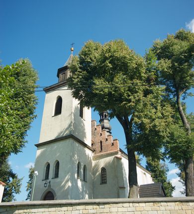 Zdjęcie nr 21: Kościół murowany z kamienia, z użyciem cegły, tynkowany; orientowany, jednonawowy. Prezbiterium węższe od nawy, zwężające się, na rzucie zbliżonym do trapezu. Przy północnej ścianie zakrystia w rzucie zbliżonym do kwadratu, z ukośną ścianą południową. Nawa na planie prostokąta, z przylegającymi od południa kruchtą i wieżą od zachodu na rzucie prostokąta. Nawa i zakrystia opięte szkarpami. 
Wnętrze nakryte stropami drewnianymi. Wątki ceglane i murowane ścian odsłonięte. Zamiast posadzki wylewka betonowa (posadzki kamienne zdemontowane). Otwór tęczowy półkolisty. Otwory okienne nawy i prezbiterium w liczbie czterech na południowej ścianie i jednego na północnej w części prezbiterium; w formie wydłużonego stojącego prostokąta zamkniętego półkoliście ze ściętymi glifami, bez obramień. Na ścianie zamykającej prezbiterium niewielki okulus. Na ścianie zachodniej niewielkie otwory okienne w formie stojącego prostokąta, dwa zamknięte ostrołukowo (przesłonięte), jeden zamknięty łukiem odcinkowym oraz dwa okulusy (zamurowane). Otwory okienne wieży ostrołukowe, z profilowanymi obramieniami kamiennymi. W zakrystii małe kwadratowe okienko przesłonięte kratownicą. Otwory drzwiowe: w wejściu do przyziemia wieży od zachodu, otwór w formie stojącego prostokąta zamkniętego łukiem ostrym, w kamiennym obramieniu zwieńczony kamienną tablicą (z datą budowy wieży „1868”), z drewnianymi drzwiami płycinowymi, dwuskrzydłowymi; w przejściu z przyziemia wieży do nawy otwór w formie stojącego prostokąta zamkniętego półkoliście (pierwotnie zamkniętego łukiem odcinkowym), przesłonięty metalową kratą; w wejściu do kruchty południowej otwór w formie stojącego prostokąta zamknięty łukiem odcinkowym, z drzwiami płycinowymi, dwuskrzydłowymi; w przejściu z kruchty do nawy otwór w formie stojącego prostokąta zamknięty półkoliście z drewnianymi drzwiami z okuciami, zamkiem i antabą; w wejściu do zakrystii od zewnętrz otwór prostokątny, z drzwiami jednoskrzydłowymi, płycinowymi; w przejściu z zakrystii do nawy otwór w formie stojącego prostokąta, w kamiennym obramieniu, z drzwiami z okuciami i zamkiem. Elewacje tynkowane, zamknięte profilowanymi gzymsami podokapowymi. Nawa, zakrystia i kruchta opięte szkarpami (przy nawie uskokowymi z daszkami okapowymi). Fasada zamknięta ceglanym szczytem, dekorowanym schodkowym krenelażem, z dwoma niewielkimi, smukłymi otworami okiennymi zamkniętymi ostrołukowo. 
Wieża trójkondygnacyjna, bez podziałów architektonicznych, druga kondygnacja zamknięta daszkiem okapowym. Zwieńczona dachem namiotowym z latarnią na planie ośmioboku, zamkniętą dachem wieżowym, pobitym blachą.
Pierwotne dachy siodłowe, o odrębnych kalenicach dla nawy i prezbiterium, kryte gontem; więźba drewniana, konstrukcji krokwiowej. Nad nawą wieżyczka na sygnaturkę z hełmem baniastym z latarnią, kryta blachą. Kruchtę przykrywa dach dwuspadowy, kryty gontem. 
