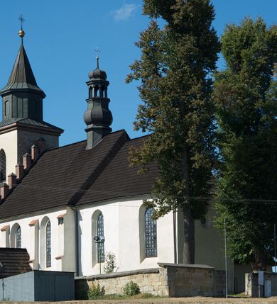Zdjęcie nr 1: Kościół murowany z kamienia, z użyciem cegły, tynkowany; orientowany, jednonawowy. Prezbiterium węższe od nawy, zwężające się, na rzucie zbliżonym do trapezu. Przy północnej ścianie zakrystia w rzucie zbliżonym do kwadratu, z ukośną ścianą południową. Nawa na planie prostokąta, z przylegającymi od południa kruchtą i wieżą od zachodu na rzucie prostokąta. Nawa i zakrystia opięte szkarpami. 
Wnętrze nakryte stropami drewnianymi. Wątki ceglane i murowane ścian odsłonięte. Zamiast posadzki wylewka betonowa (posadzki kamienne zdemontowane). Otwór tęczowy półkolisty. Otwory okienne nawy i prezbiterium w liczbie czterech na południowej ścianie i jednego na północnej w części prezbiterium; w formie wydłużonego stojącego prostokąta zamkniętego półkoliście ze ściętymi glifami, bez obramień. Na ścianie zamykającej prezbiterium niewielki okulus. Na ścianie zachodniej niewielkie otwory okienne w formie stojącego prostokąta, dwa zamknięte ostrołukowo (przesłonięte), jeden zamknięty łukiem odcinkowym oraz dwa okulusy (zamurowane). Otwory okienne wieży ostrołukowe, z profilowanymi obramieniami kamiennymi. W zakrystii małe kwadratowe okienko przesłonięte kratownicą. Otwory drzwiowe: w wejściu do przyziemia wieży od zachodu, otwór w formie stojącego prostokąta zamkniętego łukiem ostrym, w kamiennym obramieniu zwieńczony kamienną tablicą (z datą budowy wieży „1868”), z drewnianymi drzwiami płycinowymi, dwuskrzydłowymi; w przejściu z przyziemia wieży do nawy otwór w formie stojącego prostokąta zamkniętego półkoliście (pierwotnie zamkniętego łukiem odcinkowym), przesłonięty metalową kratą; w wejściu do kruchty południowej otwór w formie stojącego prostokąta zamknięty łukiem odcinkowym, z drzwiami płycinowymi, dwuskrzydłowymi; w przejściu z kruchty do nawy otwór w formie stojącego prostokąta zamknięty półkoliście z drewnianymi drzwiami z okuciami, zamkiem i antabą; w wejściu do zakrystii od zewnętrz otwór prostokątny, z drzwiami jednoskrzydłowymi, płycinowymi; w przejściu z zakrystii do nawy otwór w formie stojącego prostokąta, w kamiennym obramieniu, z drzwiami z okuciami i zamkiem. Elewacje tynkowane, zamknięte profilowanymi gzymsami podokapowymi. Nawa, zakrystia i kruchta opięte szkarpami (przy nawie uskokowymi z daszkami okapowymi). Fasada zamknięta ceglanym szczytem, dekorowanym schodkowym krenelażem, z dwoma niewielkimi, smukłymi otworami okiennymi zamkniętymi ostrołukowo. 
Wieża trójkondygnacyjna, bez podziałów architektonicznych, druga kondygnacja zamknięta daszkiem okapowym. Zwieńczona dachem namiotowym z latarnią na planie ośmioboku, zamkniętą dachem wieżowym, pobitym blachą.
Pierwotne dachy siodłowe, o odrębnych kalenicach dla nawy i prezbiterium, kryte gontem; więźba drewniana, konstrukcji krokwiowej. Nad nawą wieżyczka na sygnaturkę z hełmem baniastym z latarnią, kryta blachą. Kruchtę przykrywa dach dwuspadowy, kryty gontem. 
