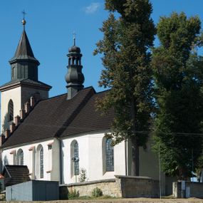 Zdjęcie nr 1: Kościół murowany z kamienia, z użyciem cegły, tynkowany; orientowany, jednonawowy. Prezbiterium węższe od nawy, zwężające się, na rzucie zbliżonym do trapezu. Przy północnej ścianie zakrystia w rzucie zbliżonym do kwadratu, z ukośną ścianą południową. Nawa na planie prostokąta, z przylegającymi od południa kruchtą i wieżą od zachodu na rzucie prostokąta. Nawa i zakrystia opięte szkarpami. 
Wnętrze nakryte stropami drewnianymi. Wątki ceglane i murowane ścian odsłonięte. Zamiast posadzki wylewka betonowa (posadzki kamienne zdemontowane). Otwór tęczowy półkolisty. Otwory okienne nawy i prezbiterium w liczbie czterech na południowej ścianie i jednego na północnej w części prezbiterium; w formie wydłużonego stojącego prostokąta zamkniętego półkoliście ze ściętymi glifami, bez obramień. Na ścianie zamykającej prezbiterium niewielki okulus. Na ścianie zachodniej niewielkie otwory okienne w formie stojącego prostokąta, dwa zamknięte ostrołukowo (przesłonięte), jeden zamknięty łukiem odcinkowym oraz dwa okulusy (zamurowane). Otwory okienne wieży ostrołukowe, z profilowanymi obramieniami kamiennymi. W zakrystii małe kwadratowe okienko przesłonięte kratownicą. Otwory drzwiowe: w wejściu do przyziemia wieży od zachodu, otwór w formie stojącego prostokąta zamkniętego łukiem ostrym, w kamiennym obramieniu zwieńczony kamienną tablicą (z datą budowy wieży „1868”), z drewnianymi drzwiami płycinowymi, dwuskrzydłowymi; w przejściu z przyziemia wieży do nawy otwór w formie stojącego prostokąta zamkniętego półkoliście (pierwotnie zamkniętego łukiem odcinkowym), przesłonięty metalową kratą; w wejściu do kruchty południowej otwór w formie stojącego prostokąta zamknięty łukiem odcinkowym, z drzwiami płycinowymi, dwuskrzydłowymi; w przejściu z kruchty do nawy otwór w formie stojącego prostokąta zamknięty półkoliście z drewnianymi drzwiami z okuciami, zamkiem i antabą; w wejściu do zakrystii od zewnętrz otwór prostokątny, z drzwiami jednoskrzydłowymi, płycinowymi; w przejściu z zakrystii do nawy otwór w formie stojącego prostokąta, w kamiennym obramieniu, z drzwiami z okuciami i zamkiem. Elewacje tynkowane, zamknięte profilowanymi gzymsami podokapowymi. Nawa, zakrystia i kruchta opięte szkarpami (przy nawie uskokowymi z daszkami okapowymi). Fasada zamknięta ceglanym szczytem, dekorowanym schodkowym krenelażem, z dwoma niewielkimi, smukłymi otworami okiennymi zamkniętymi ostrołukowo. 
Wieża trójkondygnacyjna, bez podziałów architektonicznych, druga kondygnacja zamknięta daszkiem okapowym. Zwieńczona dachem namiotowym z latarnią na planie ośmioboku, zamkniętą dachem wieżowym, pobitym blachą.
Pierwotne dachy siodłowe, o odrębnych kalenicach dla nawy i prezbiterium, kryte gontem; więźba drewniana, konstrukcji krokwiowej. Nad nawą wieżyczka na sygnaturkę z hełmem baniastym z latarnią, kryta blachą. Kruchtę przykrywa dach dwuspadowy, kryty gontem. 
