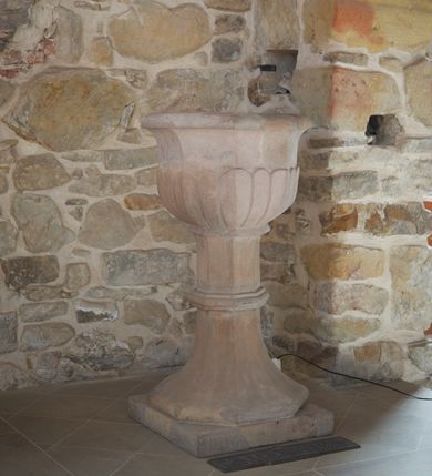 Zdjęcie nr 1: Chrzcielnicą ustawiona na niskiej podstawie na planie kwadratu. Płaszcz stopy na planie ośmioboku, zwężający się ku  górze, zamknięty profilowanym, ośmiobocznym pierścieniem. Trzon o przekroju ośmiobocznym. Czara o przekroju ośmiobocznym, wypukła, z wywiniętym brzegiem, w dolnej części dekorowana imitacją puklowania. 

