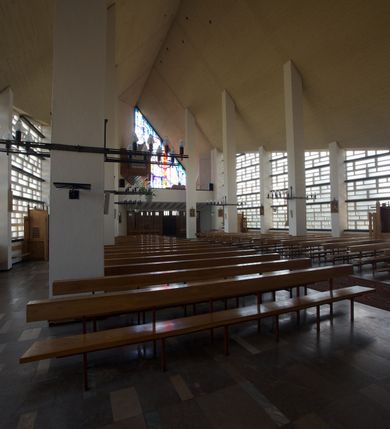 Zdjęcie nr 9: Okładzina ceramiczna pokrywa dwie ściany zamykające prezbiterium, łączące się pod kątem rozwartym i doświetlone pośrodku przez wpadające z górnego świetlika światło. Płyty są płaskorzeźbione i opracowane reliefowo, w kolorystyce błękitnej i seledynowej spływającej od szczytu ściany i przechodzącej w intensywną czerwień i brązy.