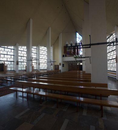 Zdjęcie nr 7: Okładzina ceramiczna pokrywa dwie ściany zamykające prezbiterium, łączące się pod kątem rozwartym i doświetlone pośrodku przez wpadające z górnego świetlika światło. Płyty są płaskorzeźbione i opracowane reliefowo, w kolorystyce błękitnej i seledynowej spływającej od szczytu ściany i przechodzącej w intensywną czerwień i brązy.